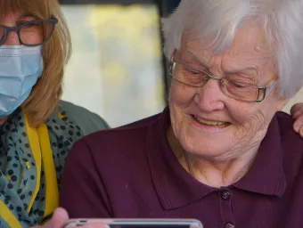 Elderly grey-haired woman with a masked carer